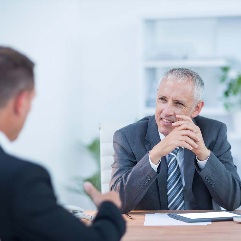 Photo of men sat at a table having a business meeting